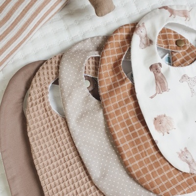 Conjunto de quatro babetes para bebé em várias cores neutras com padrões e textura distintas