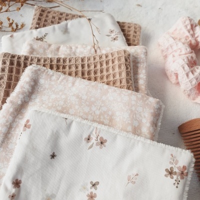 Paninhos de tecido com padrões florais e quadriculados em tons bege e rosa com elástico de cabelo e pente
