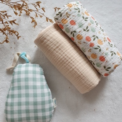 Duas mantas de algodão e um saco xadrez verde e branco em fundo branco com ramo seco