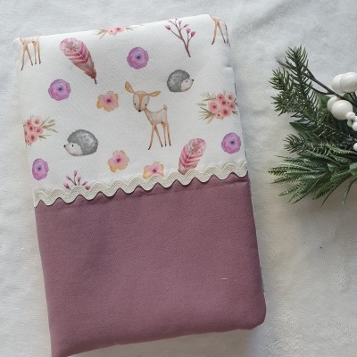 Capa de tecido branco com padrão animal e rosa velho com fita de zig-zag e decoração vegetal