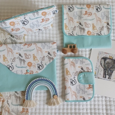 Conjunto de acessórios em tecido azul-água com padrão de animais da savana e objetos decorativos em fundo branco