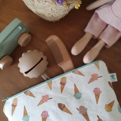 Bolsa com padrão de gelados coloridos, pente de madeira e brinquedos sobre mesa