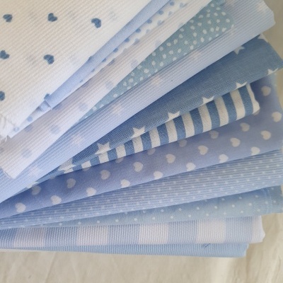 Tecidos azuis e brancos com vários padrões empilhados sobre fundo branco