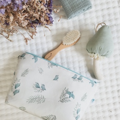 Necessaire floral com escova e brinquedo de tecido sobre manta branca