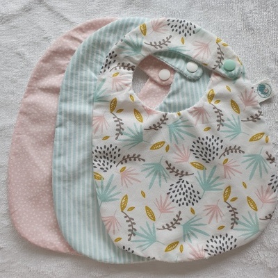 Três babetes para bebé com padrões diferentes sobre fundo branco