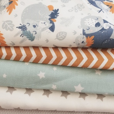 Pilha de tecidos com padrões variados, ursinhos, ziguezague e estrelas.