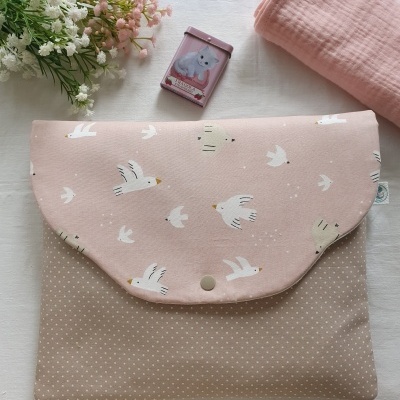 bolsa de tecido rosa e bege com padrão de gaivotas e pontos sobre superfície branca com flores e caixa pequena