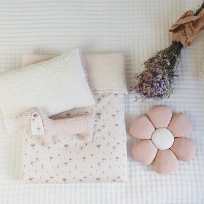 Conjunto de acessórios têxteis em tons pastel com motivo floral sobre manta branca