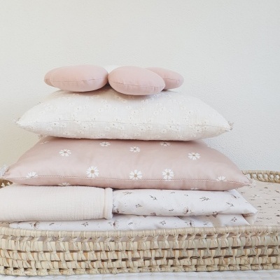 Conjunto de almofadas e têxteis pastel empilhados numa base de palha