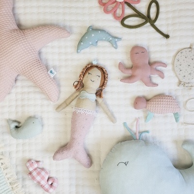 Brinquedos de tecido macio em manta branca sobre superfície clara