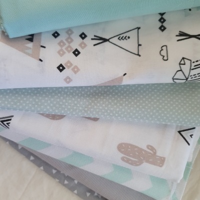 Seis tecidos em tons pastel e neutros com padrões diversos em cima de superfície clara