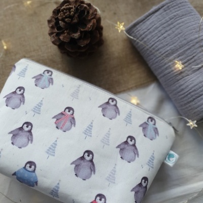 Estojo branco com padrão de pinguins e árvores de Natal, pinha e tecido cinza com luzes de estrelas