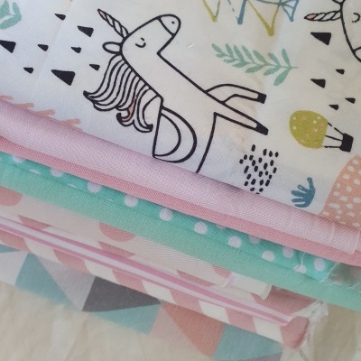 Tecidos coloridos com padrões de unicórnios, folhas, bolinhas e formas geométricas