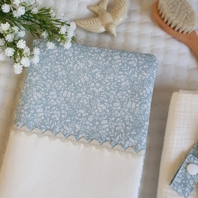 Toalha branca com topo azul claro floral, escova de cerdas naturais, pássaro cerâmico e flores artificiais