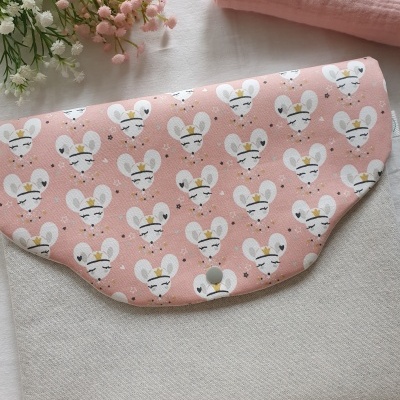 Mala pequena rosa com padrão de ratos brancos e botão metálico sobre tecido branco e flores ao lado