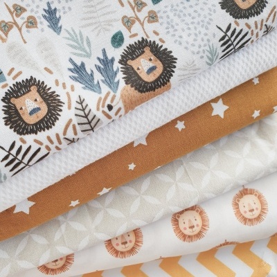 Tecidos com estampados de leão, folhas, estrelas e padrões geométricos em várias cores sobre madeira