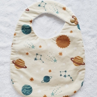 Babete de bebé com padrão de planetas e estrelas