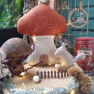 Decoração natalícia com cogumelo de tecido laranja, esquilo branco, base de madeira e luzes