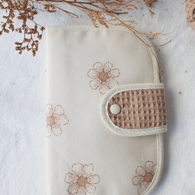 Carteira creme com flores castanhas e fecho bege com textura de waffle