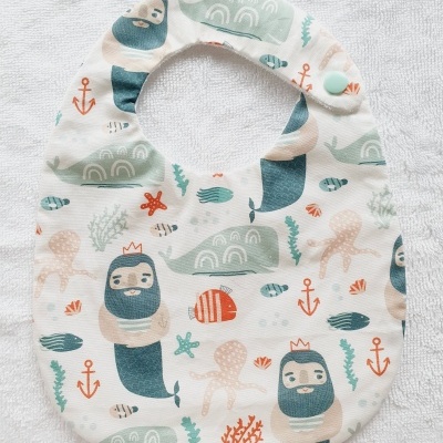 Babete com padrão de sereias e elementos marinhos coloridos