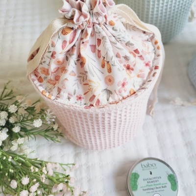 Saco de tecido floral rosa ao lado de lata metálica e flores artificiais