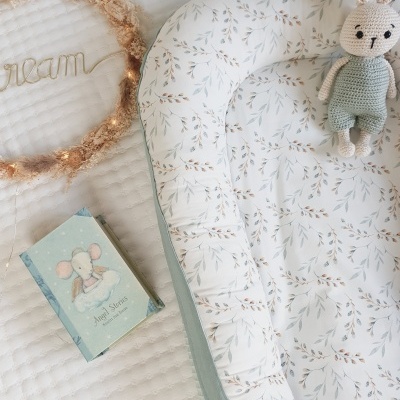 Cama de bebé com padrão de folhas, brinquedo coelho de croché, livro azul e decoração 'dream'