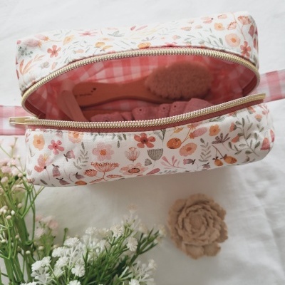 Necessaire floral com fecho dourado e interior xadrez rosa contendo escova de cabelo
