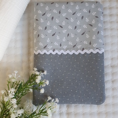 Capa de tecido bicolor com padrão de folhas e bolinhas, decorada com fita ondulada branca