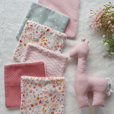 Brinquedos têxteis para bebé em tons rosa e pastel com padrões florais e de corações