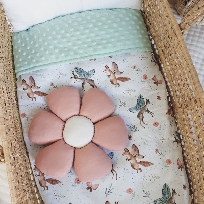 Berço de vime com lençol estampado e almofada em forma de flor