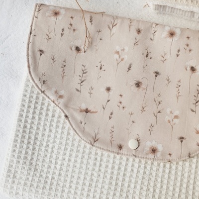 Mala de algodão floral com botão branco sobre toalha branca de textura waffle