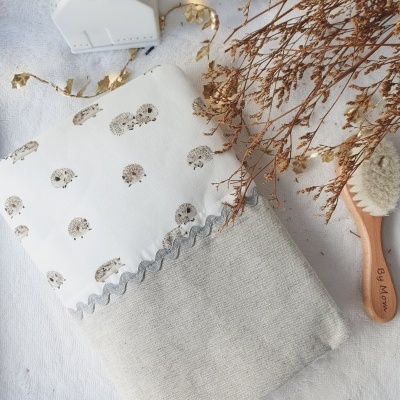 Almofada cinza e branca com padrão de ouriços, escova de madeira e ramo seco