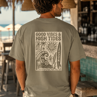 T-shirt bege com estampa castanha clara e texto GOOD VIBES & HIGH TIDES em ambiente de bar de praia