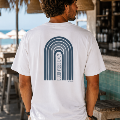 Camiseta branca com estampa azul escura GOOD VIBES ONLY nas costas, ambientação à beira-mar