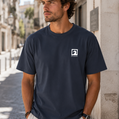 Homem com camiseta azul escura BYnahola em rua com calçada de pedra