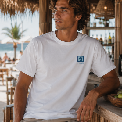 Homem com t-shirt branca com logótipo azul num bar de praia de madeira