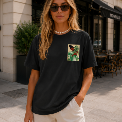Mulher a usar t-shirt preta com estampa de mulher com folhas, óculos de sol e colar de conchas