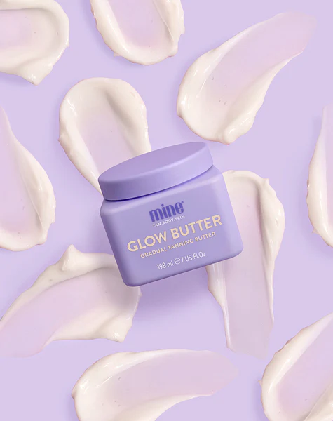 Glow Butter - Manteiga Corporal Hidratante + Bronzeado Gradual Frasco lilás de Glow Butter com manchas de creme lilás ao redor