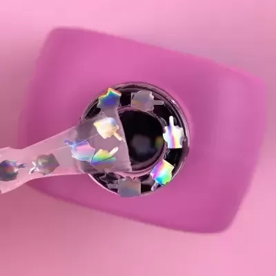 Esmalte preto com partículas holográficas numa superfície rosa