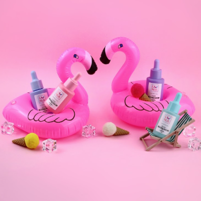 Boias insufláveis cor-de-rosa em forma de flamingos com frascos de cosméticos rosa e azul da marca LUNA, sobre fundo rosa, decoradas com cubos transparentes e figuras de gelados em cone.