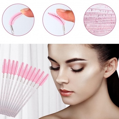 Escovas descartáveis para pestanas e sobrancelhas rosa com cabo transparente ao lado do rosto de uma mulher.
