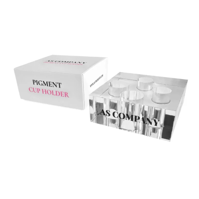 Porta-copos de acrílico transparente com 4 espaços e caixa branca ao lado.