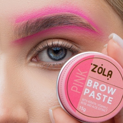 Lata rosa de pomada para sobrancelhas perto do olho com sobrancelha pintada de rosa