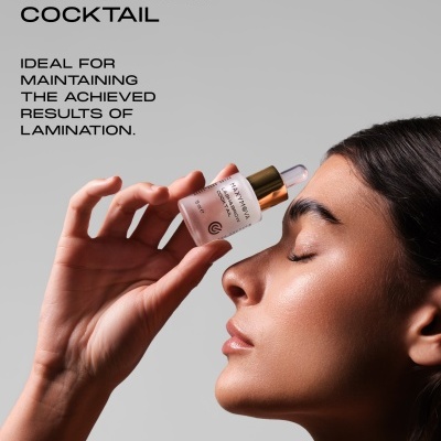 Produto para pestanas e sobrancelhas MAXYMOVA Lash&Brow Cocktail com conta-gotas ao lado do rosto de mulher