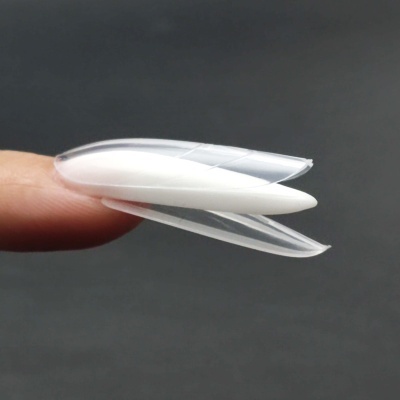 Unha postiça branca fina curva numa ponta de dedo em fundo cinzento