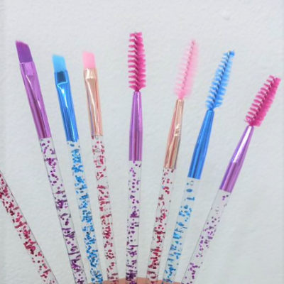 Sete pincéis de maquilhagem coloridos com cabos brancos desenhados e cerdas coloridas