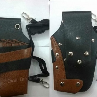 Bolsa castanha e preta com rebites metálicos e alça ajustável para transporte de objetos.