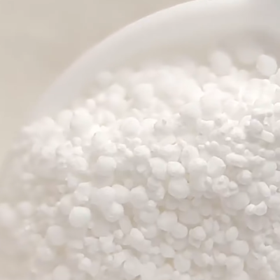 Granulados brancos esféricos num recipiente branco em close-up