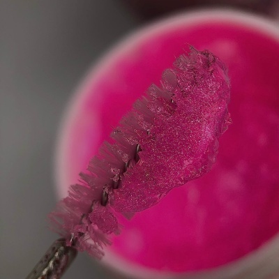 Pincel com gel cor-de-rosa em cima de um recipiente branco