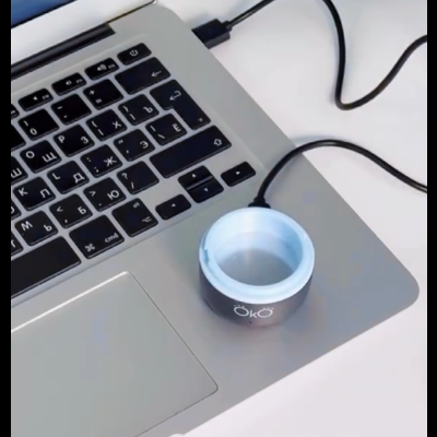 Computador portátil cinzento com dispositivo circular preto e branco ligado por USB